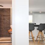 Bad mit Dusche und Waschmaschine. Küche mit Barhocker und Fenster.