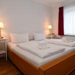 Ein Schlafzimmer mit Doppelbett, zwei Nachttischen und roten Vorhängen.