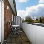 Terrasse mit Tisch und zwei Stühlen, roter Backsteinmauer und Blick auf Nachbarhäuser.