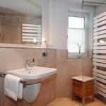 Badezimmer mit Waschbecken, Spiegel, Dusche und Heizkörper.