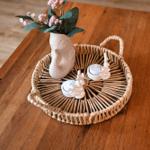 Holztisch mit geflochtenem Korb, Vasen und Kerzenhaltern.