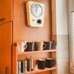 Küche mit Holzschränken, Muggen und einem Wanduhrenmodell.