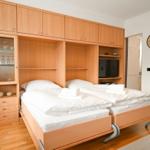 Zwei Betten unter Holzmöbeln mit Schrank und Fernseher.