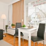 Ein Essbereich mit weißem Tisch, zwei schwarzen Stühlen und Blick auf die Straße.