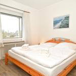 Schlafzimmer mit Doppelbett, Fenster und Wandbild.