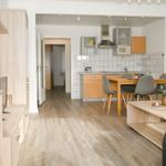 Wohnbereich mit Küche, Esstisch und Sofa. Holzboden und moderne Einrichtung.