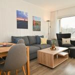 Wohn- und Essbereich mit Sofa, Tisch und Blick auf Balkon.