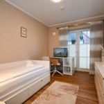 Schlafzimmer mit Bett, Schreibtisch und TV. Fenster mit Jalousien und Vorhängen.