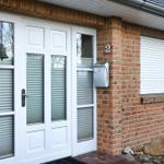 Haus mit weißer Haustür, Briefkasten und Ziffer 2 an der Backsteinfassade.