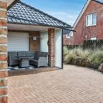 Terrasse mit Sitzgruppe unter Dach, gepflasterter Hof und Gartenbereich mit Steinen.