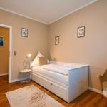 Schlafzimmer mit Bett, Stuhl und Wandbildern.