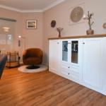 Wohnbereich mit weißen Schränken, braunem Sessel und Holzboden.