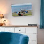 Ein Raum mit blauem Sessel, Schrank und Wandbild eines Strandes.