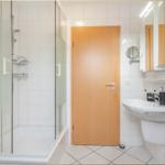 Badezimmer mit Dusche, Waschbecken und Spiegel.