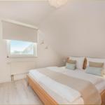 Schlafzimmer mit Dachschrägen, Bett, Fenster und Heizung.