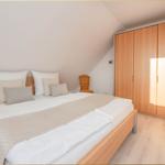 Schlafzimmer mit Doppelbett, Kleiderschrank und Wickerstuhl unter Dachschrägen.