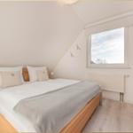 Schlafzimmer mit Dachschräge, Bett, Fenster und Kleiderschrank.