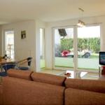 Wohnbereich mit Sofa, Fernseher und Terrasse mit Gartenblick.