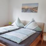 Zimmer mit Doppelbett, zwei Nachttischen und Wandbild