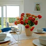 Esstisch mit Blumenvase und Stühlen vor Fenster mit Gartenblick.