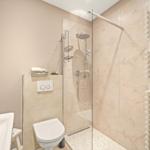 Badezimmer mit Dusche, Toilette und Waschbecken. Fliesen und Spiegel sind sichtbar.