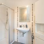 Badezimmer mit Duschkabine, Waschbecken und Spiegel