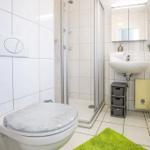 Badezimmer mit Dusche, Waschbecken und Toilette. Grün Teppich und Handtuchhalter.