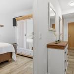 Schlafzimmer mit Bett, Kleiderschrank und Flur mit Schminktisch.