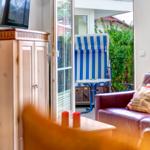 Wohnzimmer mit Sofa und Blick auf Terrasse mit Strandkorb.