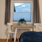 Ein Schreibtisch mit zwei Stühlen vor einem Fenster mit Blick auf Berge.