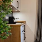 Küche mit Holzoberfläche, schwarzer Kaffeemaschine und Fenster mit Jalousie.