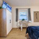 Zimmer mit Bett, Schreibtisch, TV und Fenster mit Bergblick.