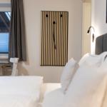 Schlafzimmer mit Bett, Schreibtisch und Wanddekoration.