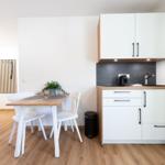 Küche mit Essplatz, Holzfußboden und weißen Schränken.