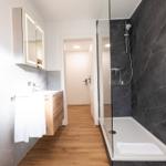 Badezimmer mit Dusche, Waschbecken und Spiegel