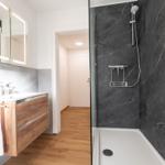 Badezimmer mit Dusche, Waschbecken und Spiegel