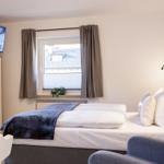 Ein Schlafzimmer mit Bett, TV und Fenster. An der Wand hängt ein Bild.