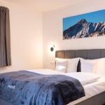 Schlafzimmer mit Doppelbett, Wandbild und Fenster mit Vorhängen.