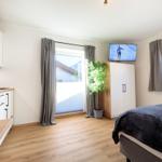 Schlafzimmer mit Bett, TV, Küchenzeile und Fenstern mit Blick.