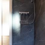 Duschkabine mit dunklem Marmor und chromfarbenem Duschset.