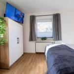Schlafzimmer mit Bett, Kleiderschrank und Fenster mit Bergblick.