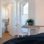 Essbereich mit Tisch und Stühlen. Im Hintergrund ist die Toilette sichtbar.