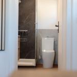 Badezimmer mit Dusche und Toilette. Marmorwände und Holzboden.