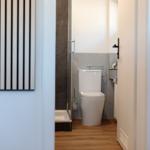 Badezimmer mit Toilette und Dusche, Holzboden und grauen Fliesen