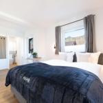 Schlafzimmer mit Bett, Fenster und Blick auf Berge. Nebenraum mit Toilette und Dusche.