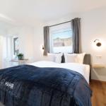 Schlafzimmer mit Doppelbett, Fensterblick und Wandbild. Nebenraum mit Toilette und Tisch.