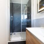 Bad mit Dusche, Waschbecken und beleuchtetem Spiegel