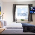 Schlafzimmer mit Bett, Fenster, TV und Wandbild.