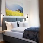 Schlafzimmer mit Bett, Wandbild und Nachttisch. Fenster mit Vorhängen.