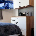 Schlafzimmer mit kleiner Küchenzeile und Fernseher an der Wand.